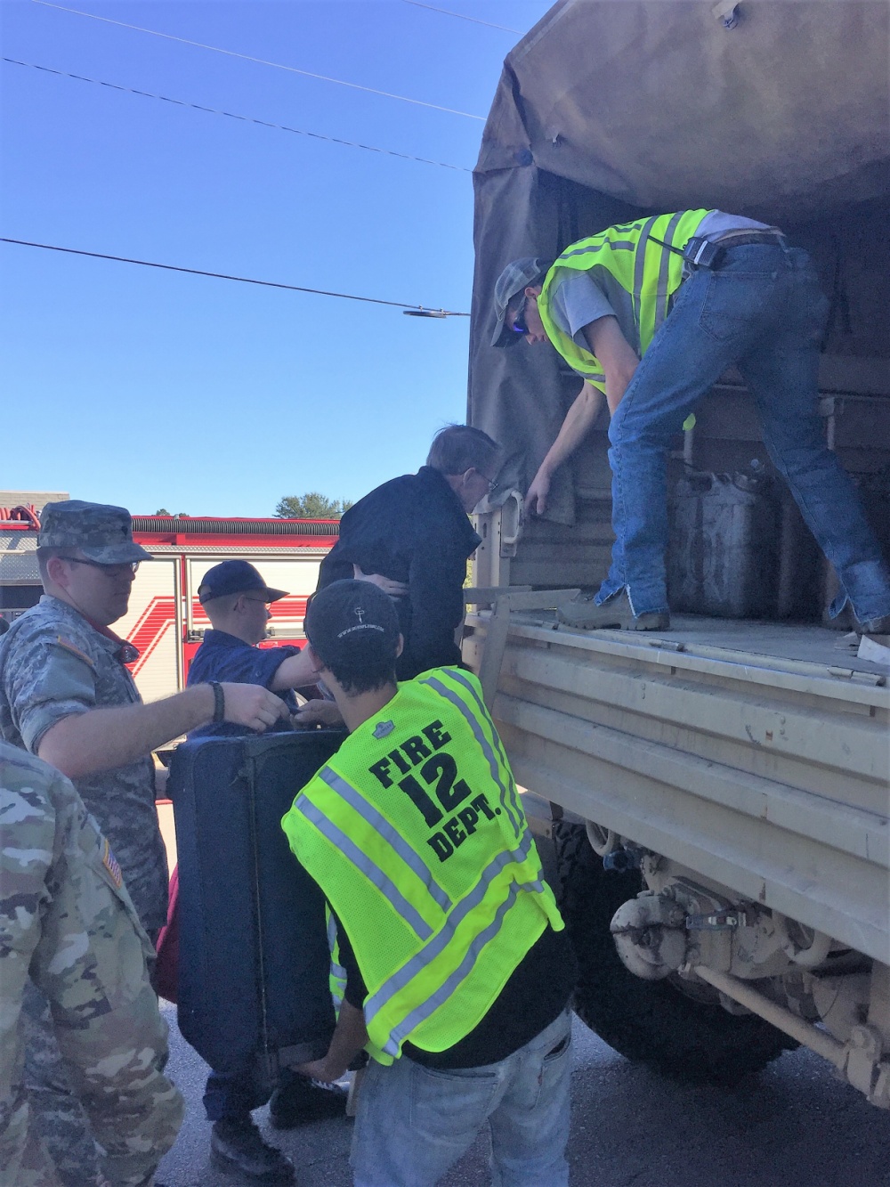 Local fire department rescue workers help flood survivors board a North Carolina Air National Guard 236th Brigade Engineer Battalion M35 2-ton cargo truck in Lumberton, North Carolina, Oct. 10, 2016. The Lumber River flooded the city after Hurricane Matthew. (U.S. Coast Guard photo by Master Chief Petty Officer Louis Coleman/Released)