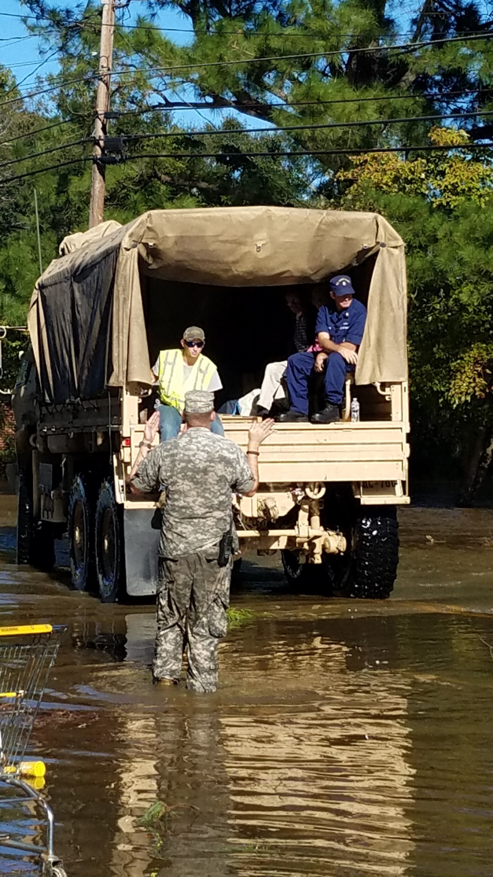 Master Chief Petty Officer Louis Coleman (right) sits with flood survivors and rescuers on a North Carolina Air National Guard 236th Brigade Engineer Battalion M35 2-ton cargo truck in Lumberton, North Carolina, Oct. 10, 2016. The Lumber River flooded the city after Hurricane Matthew. (U.S. Coast Guard photo by Petty Officer 1st Class James Prosser/Released)
