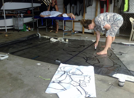 Last minute artwork on the mainsail of Read BTW the Lines (Adam Syme/Daniel Farthing) before the teams head out for Day 1. Credit: Tracey Johnstone